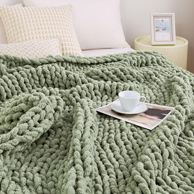 Admitrack chunky knit blanket in sage green draped over a sofa for cozy living room warmth.