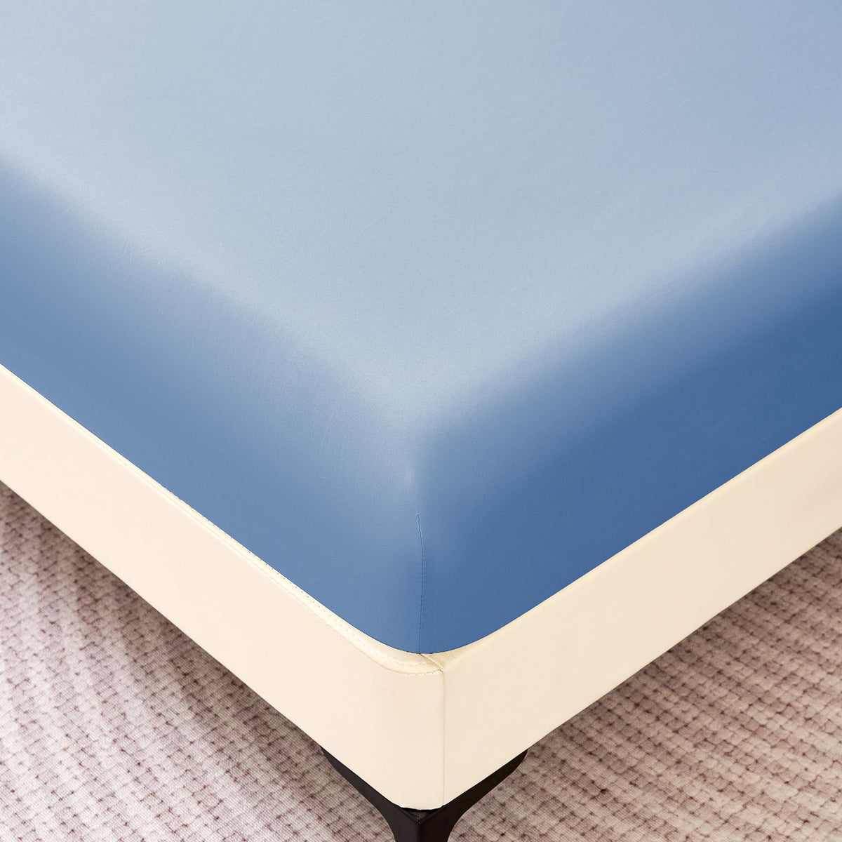 Blue fitted sheet laid on bed demonstrating color and snug fit.