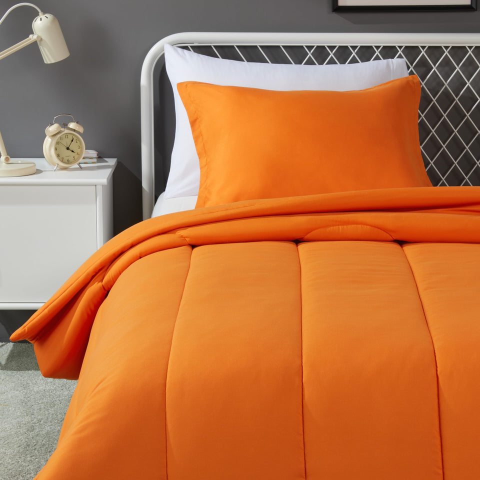Amazon Basics kids comforter and twin sham in bright orange on a bed, cozy and inviting.