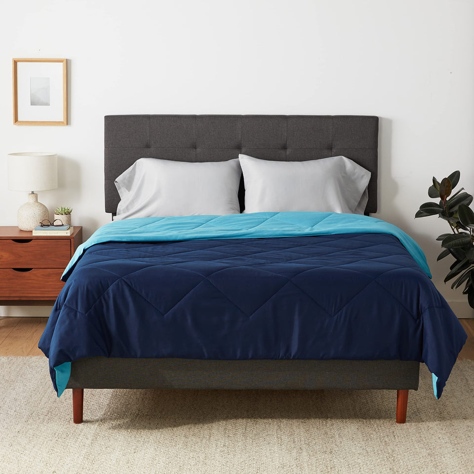 Amazon Basics soft reversible comforter in navy for two looks on a bed.