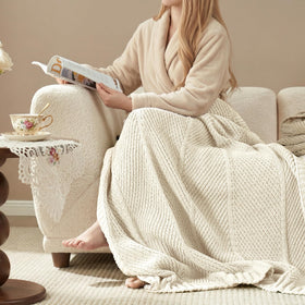 Amélie Home ivory knit throw draped on sofa for cozy lounging.