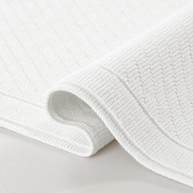 Arkwright 100% cotton bath rug with textured weave for absorbent comfort.