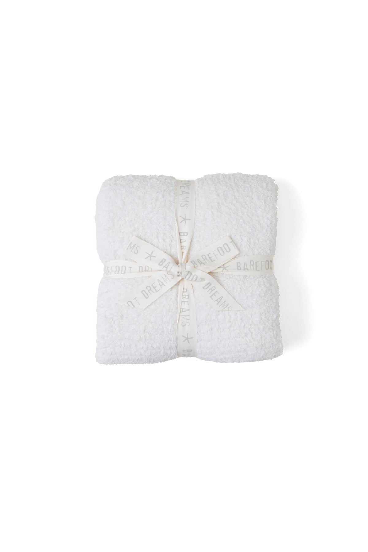 Barefoot Dreams CozyChic Throw in cream folds with luxurious softness for cozy evenings.