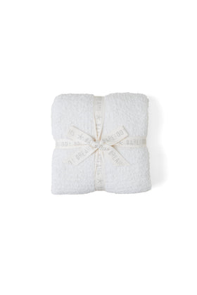Barefoot Dreams CozyChic Throw in cream folds with luxurious softness for cozy evenings.