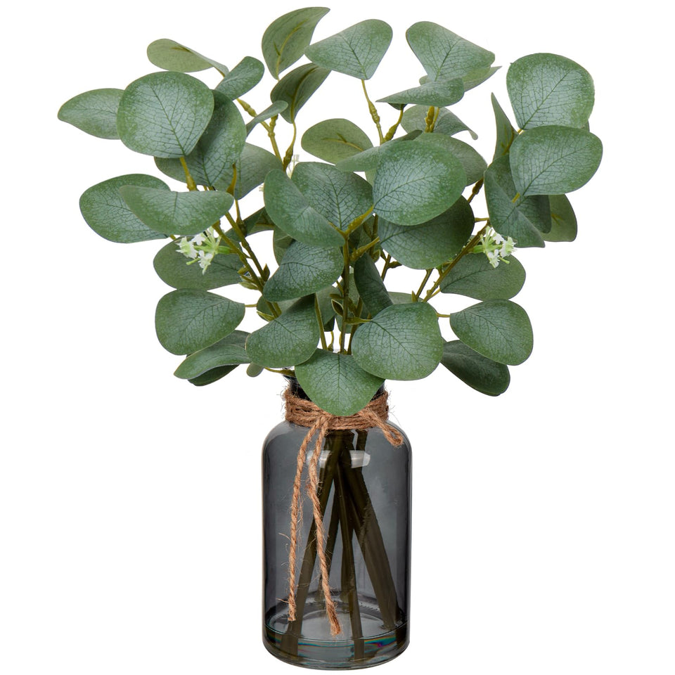 Briful artificial eucalyptus stems in a black glass vase with faux water for lifelike centerpiece.