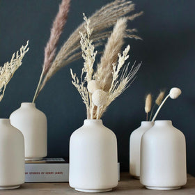 Carrot's Den six white mini ceramic vases on table for elegant home styling.