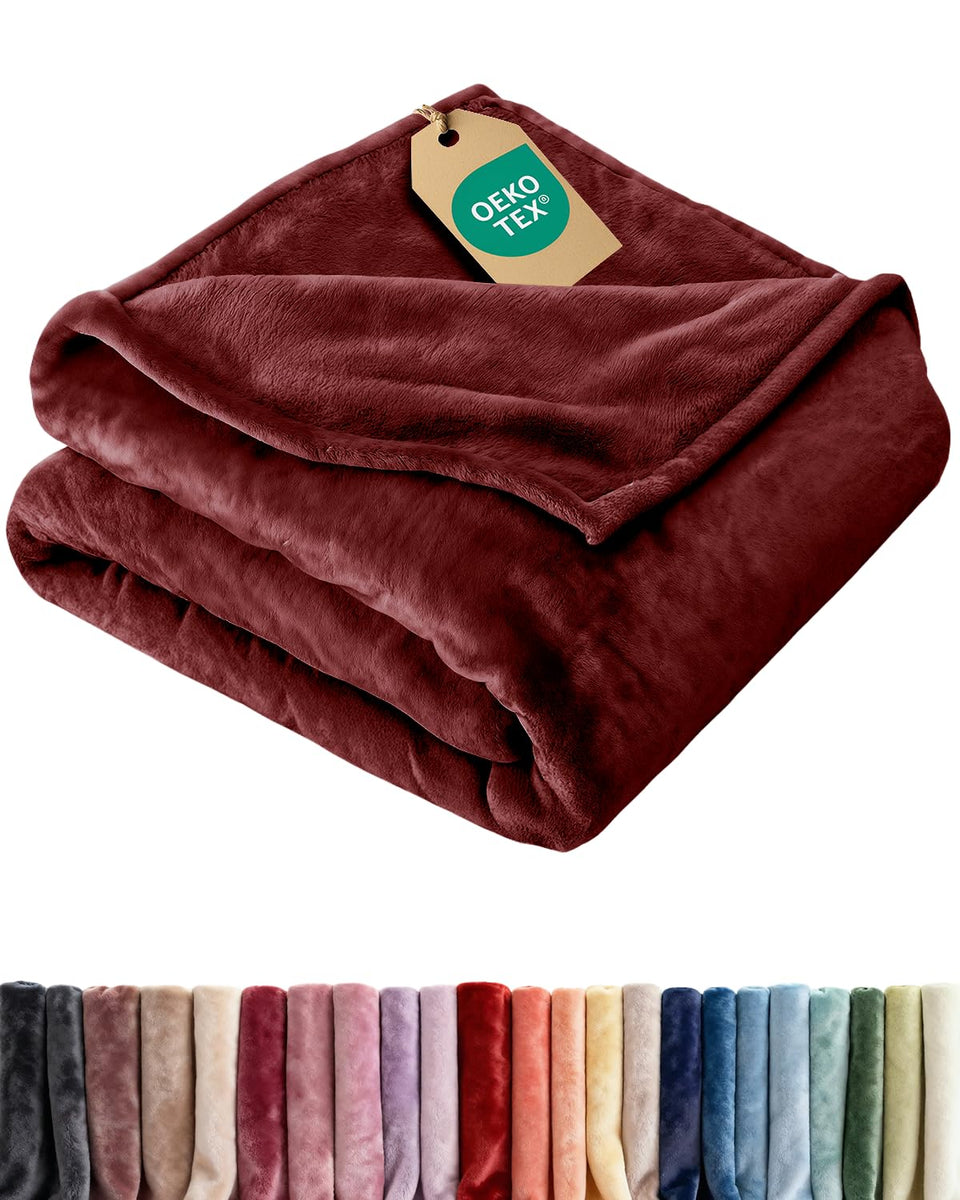CGK Unlimited Ultra Soft Fleece Blanket in Burgundy on bed offers year-round comfort and softness.