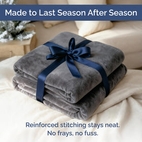 Dark grey CGK Unlimited fleece blanket on bed showing neutral style