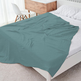 Cosy Family muslin blanket green folded on sofa for cozy lounge moments.
