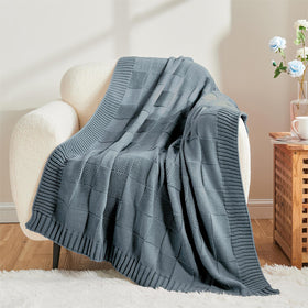 CozeCube knitted blanket drapes over bed for cozy nights and warmth.
