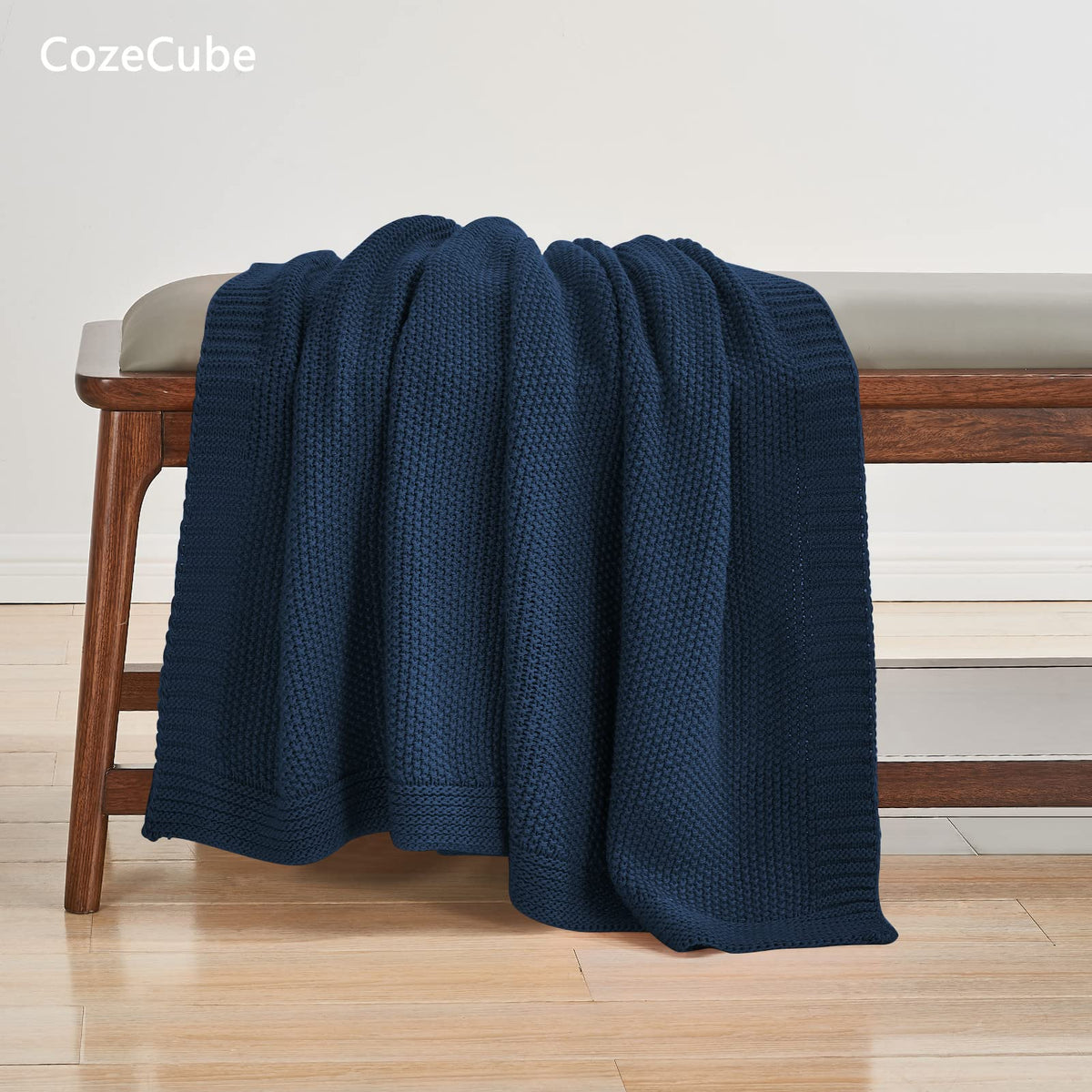CozeCube navy blue folded blanket on bed provides inviting warmth and decorative touch.