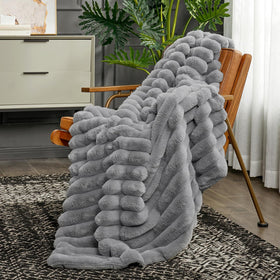 Cozy Bliss faux fur throw draped over bed for luxe look.