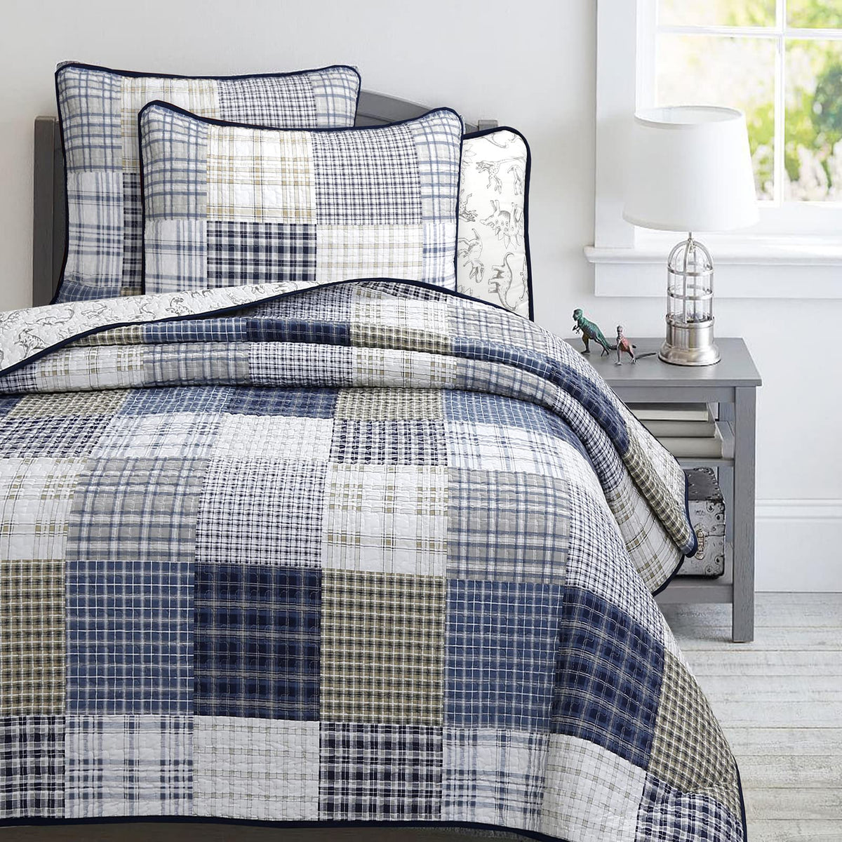 Benjamin dinosaur quilt with navy plaid and white accents for kids' room styling.