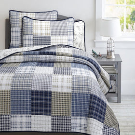 Benjamin dinosaur quilt with navy plaid and white accents for kids' room styling.