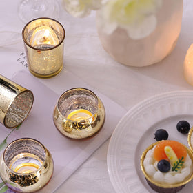 DEVI gold mercury glass votive holders with textured finish catching candlelight.
