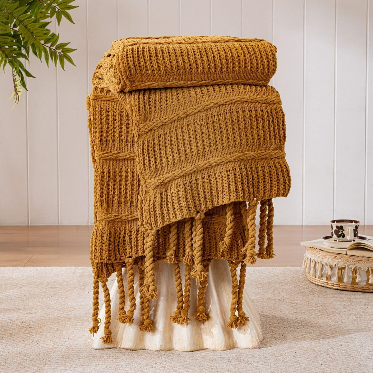 Down Home Boho knitted chenille blanket with tassels in amber brown over a cozy living space for comfortable warmth