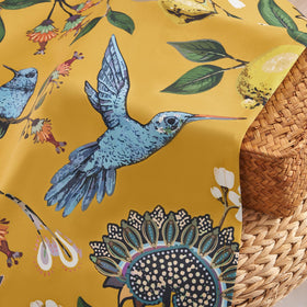 Drapenova hummingbird and lemon print on mustard background in a living room setting.