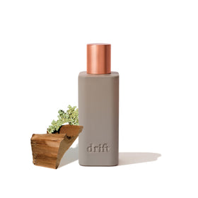 Drift Teak room spray bottle releases warm, woody notes for a cozy home.
