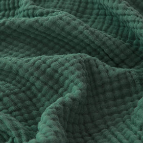 EMME cotton muslin blanket folded in forest green showing soft texture.