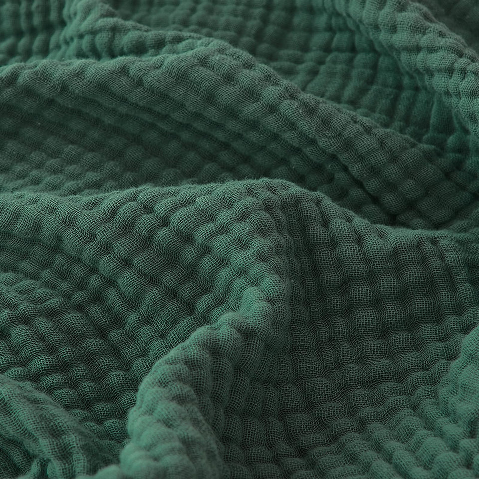 EMME cotton muslin blanket folded in forest green showing soft texture.
