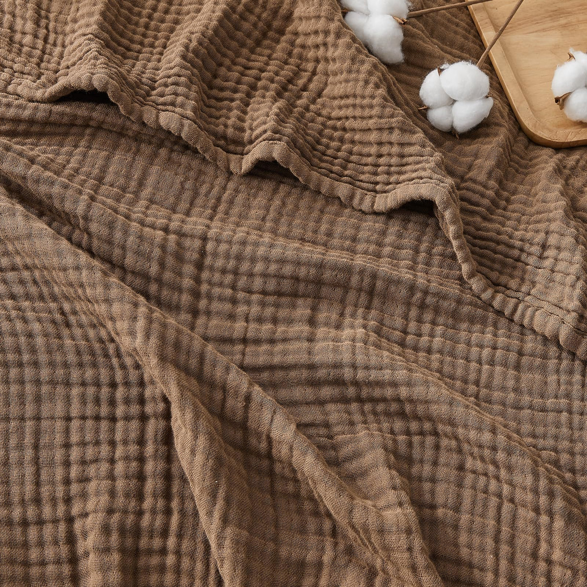 EMME cotton muslin throw in brown draped on sofa for cozy warmth