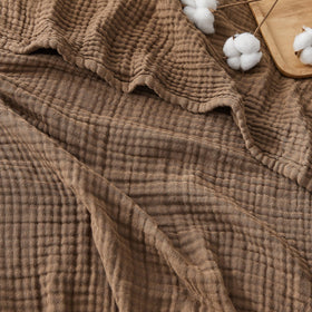 EMME cotton muslin throw in brown draped on sofa for cozy warmth
