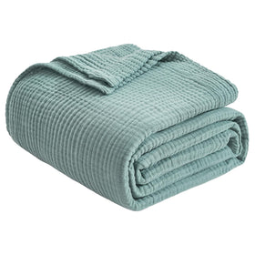 EMME cotton throw blanket on sofa in teal, adding cozy texture to living spaces.