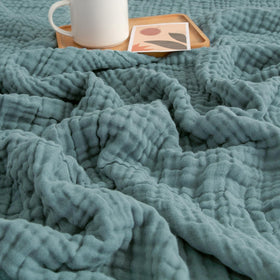 EMME Muslin Blanket teal 60x80 on a comfy couch showing all-season coverage