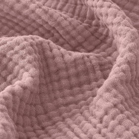 EMME muslin throw blanket in dusty pink on couch for cozy warmth.