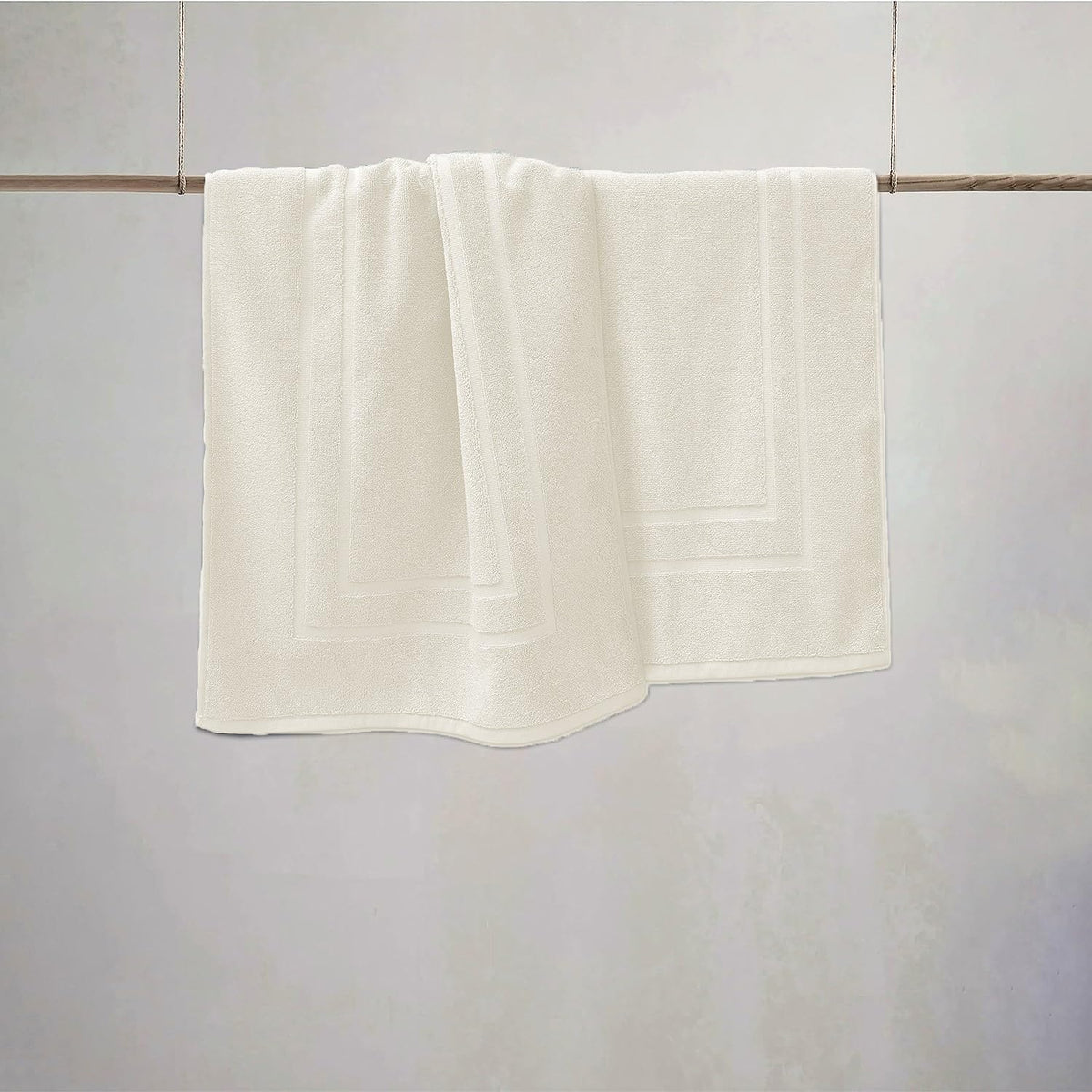 FEATHER & STITCH NEW YORK ivory bath mat adds calm, clean decor to any bathroom.