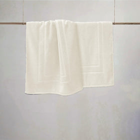FEATHER & STITCH NEW YORK ivory bath mat adds calm, clean decor to any bathroom.