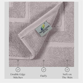Pair of taupe bath mats from Feather and Stitch New York laid by the shower.