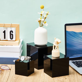 Geetery jewelry display risers highlight pieces on black acrylic stands.