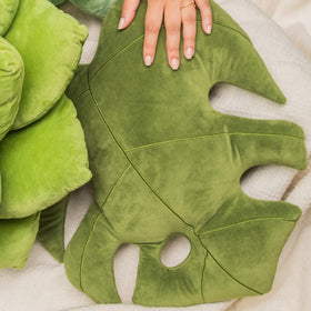 Green Philosophy Co. Monstera Leaf Pillow on couch provides plush support for neck and back.