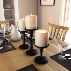 HB Design Co. matte black candle holders on fireplace mantel for warm ambiance.