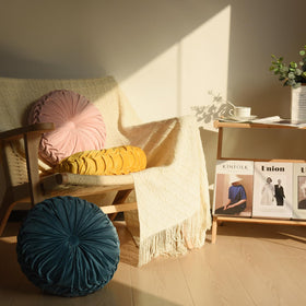 HIG yellow ruched velvet round pillow on sofa acts as a chic accent.