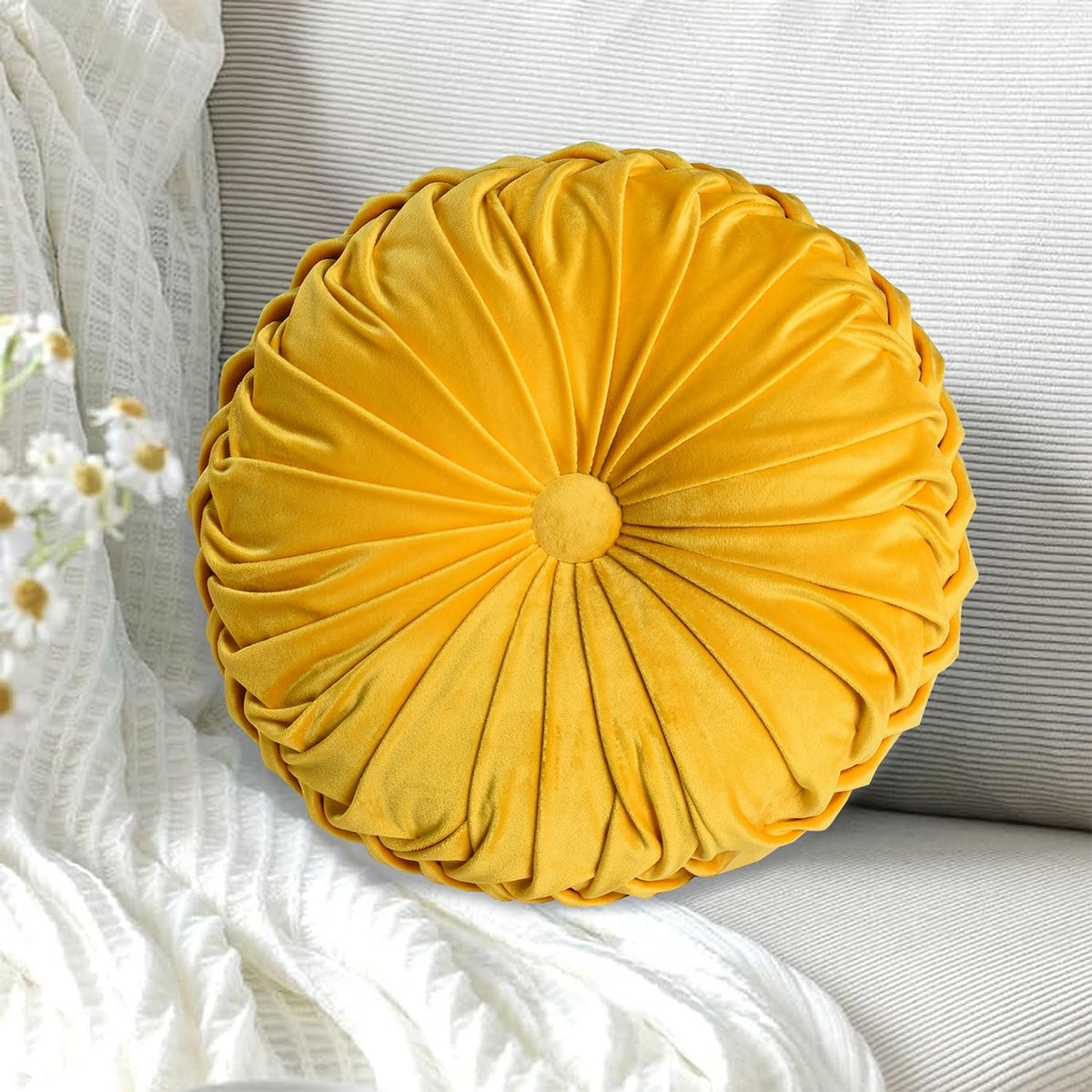 HIG yellow ruched velvet round pillow on sofa adds cozy decor.