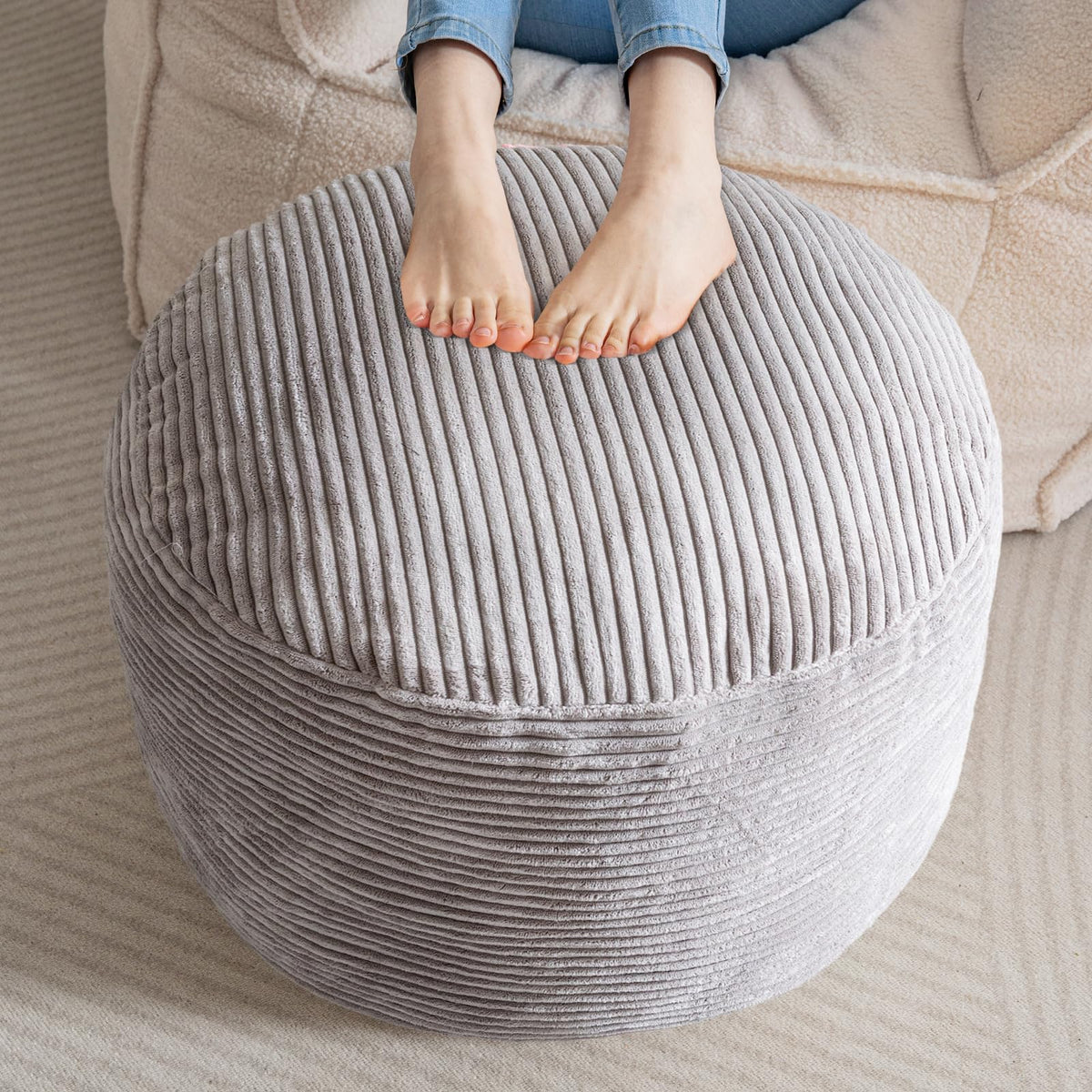 HIGOGOGO grey round pouf ottoman serves as a cozy foot rest in living spaces.