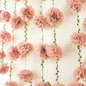 Homarkable pink tissue pom-pom garland close-up with greenery for nature-inspired decor
