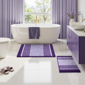 HOMEIDEAS purple bathroom rugs set in bathroom by sink and tub area.