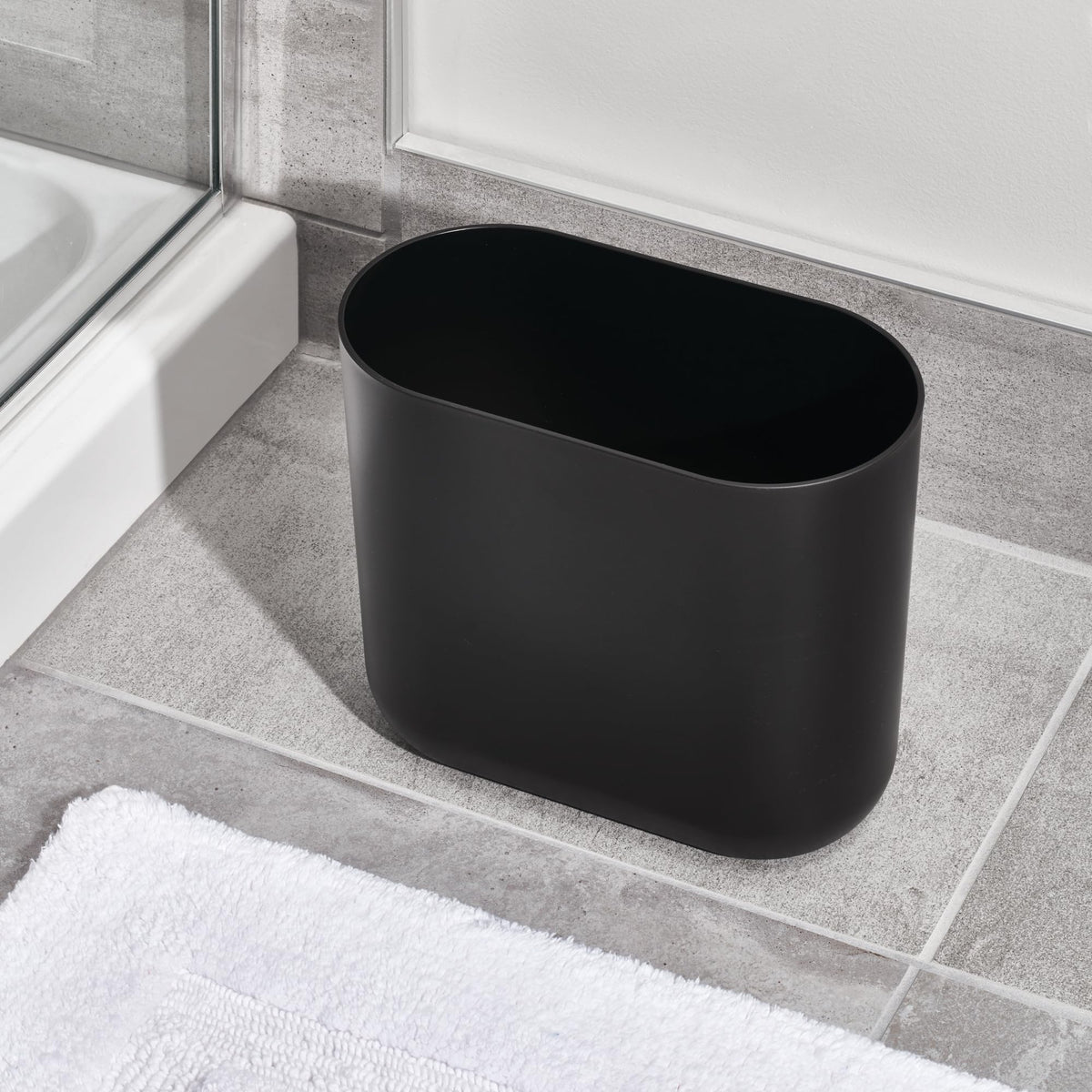 iDesign Cade Oval Trash Can’s black finish adds a modern touch to any small room.