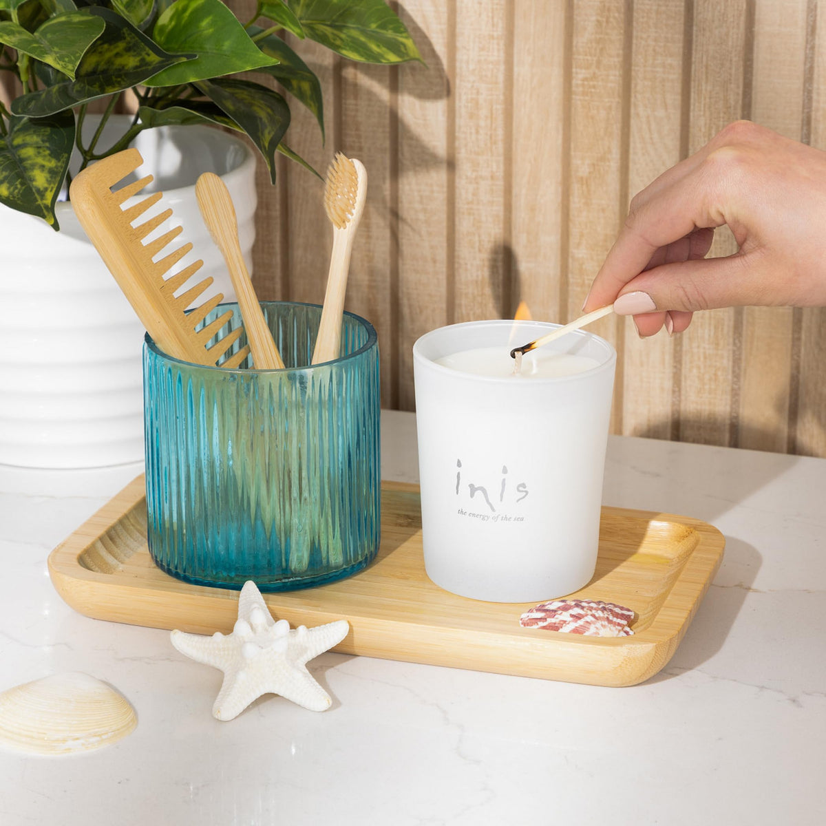 Inis candle in white frosted glass vessel adds soft glow to a bedside table.