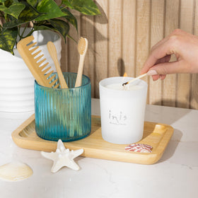 Inis candle in white frosted glass vessel adds soft glow to a bedside table.