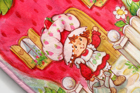 Jay Franco Strawberry Shortcake plush blanket folded display, lightweight warmth for travel.