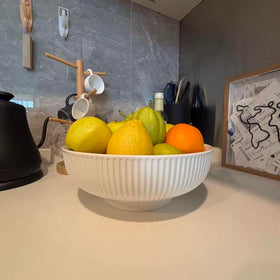 JolieJulie fruit bowl on a kitchen island with fresh fruit for decor.