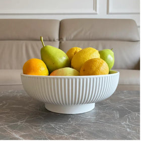 JolieJulie cream white ceramic bowl resting on open shelf as decor accent.