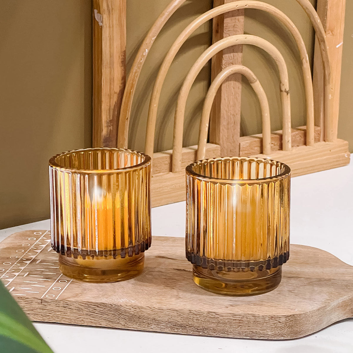 Kate Aspen amber ribbed glass tealight holder close-up, highlighting warm candlelight