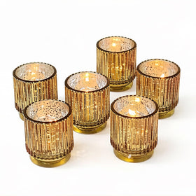 Kate Aspen gold ribbed votive holders arranged on a tray for warm holiday glow.
