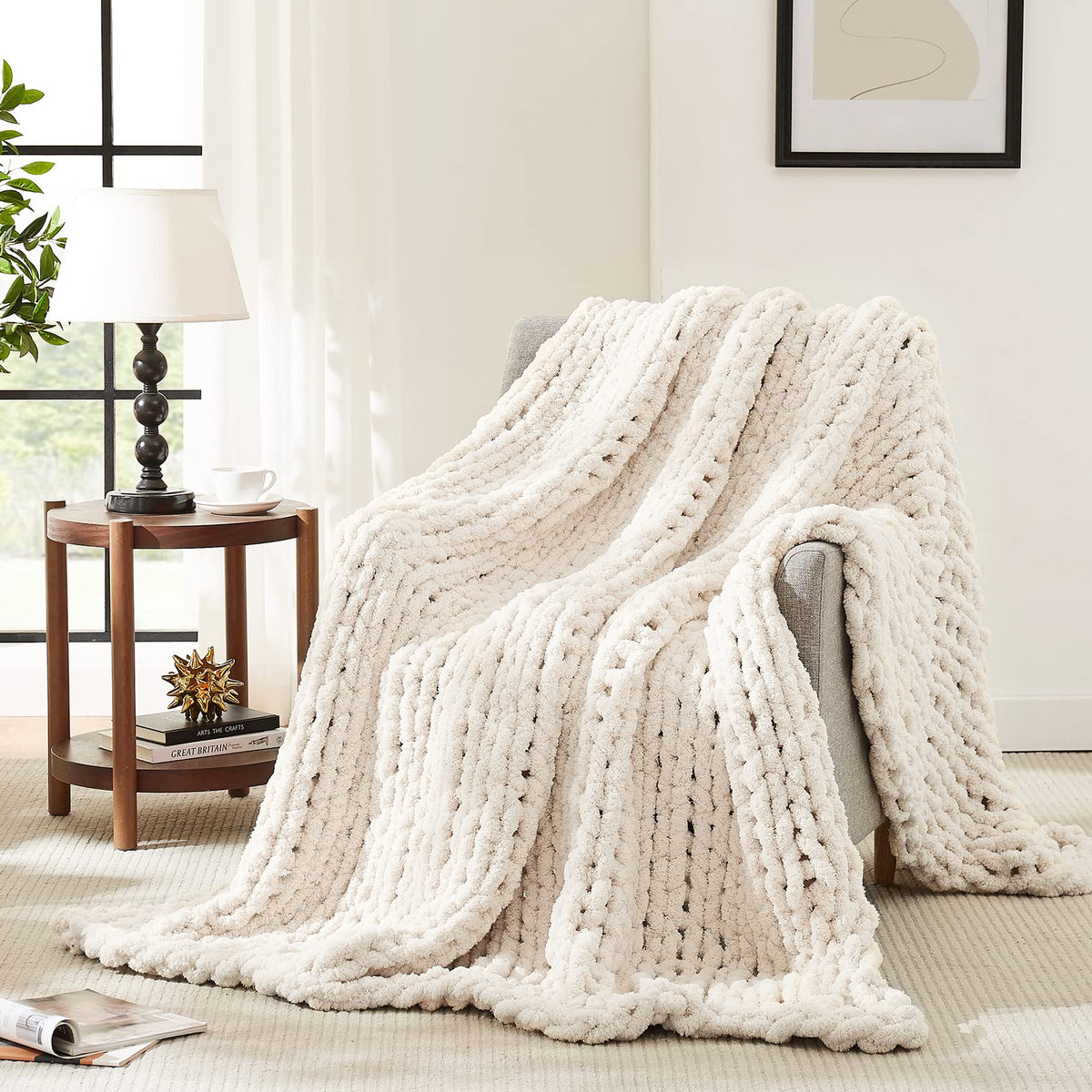 L'AGRATY chunky knit blanket in ivory draped over sofa for cozy living room ambiance.
