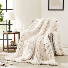 L'AGRATY chunky knit blanket in ivory draped over sofa for cozy living room ambiance.